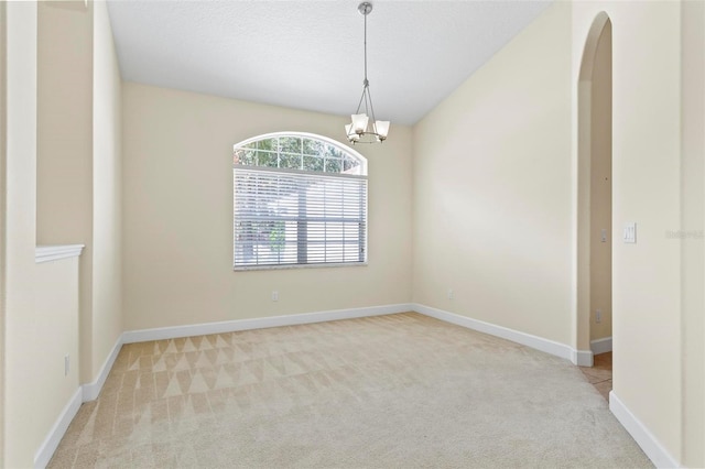 carpeted spare room with a notable chandelier and a textured ceiling