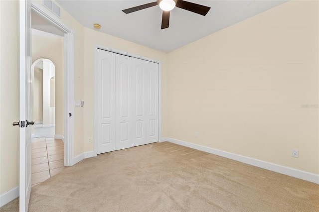 unfurnished bedroom featuring a closet, light colored carpet, and ceiling fan