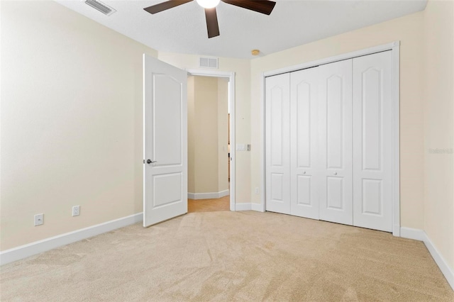 unfurnished bedroom featuring light colored carpet, ceiling fan, and a closet