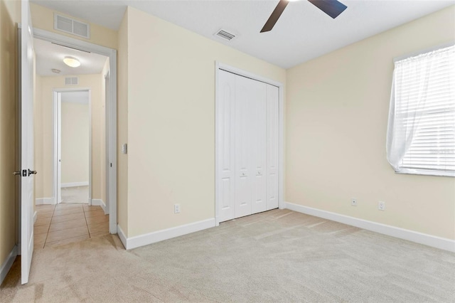 unfurnished bedroom featuring a closet, light colored carpet, and ceiling fan