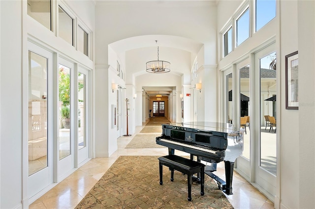 miscellaneous room with an inviting chandelier and a towering ceiling