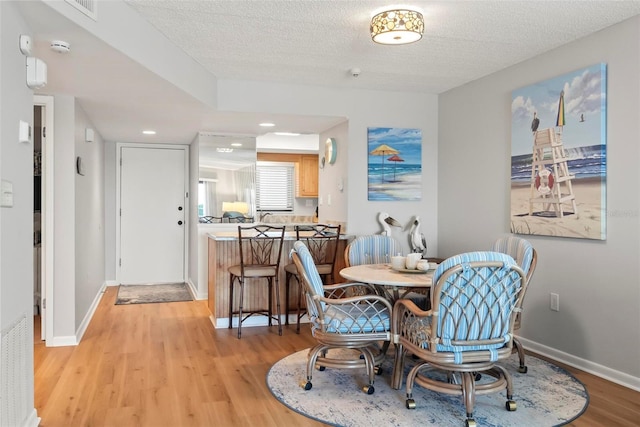 dining space featuring light hardwood / wood-style floors and a textured ceiling