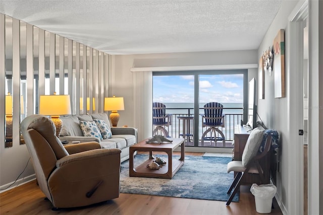 living room featuring a water view, a textured ceiling, and hardwood / wood-style flooring