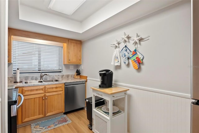 kitchen featuring light hardwood / wood-style flooring, stainless steel dishwasher, a tray ceiling, and sink