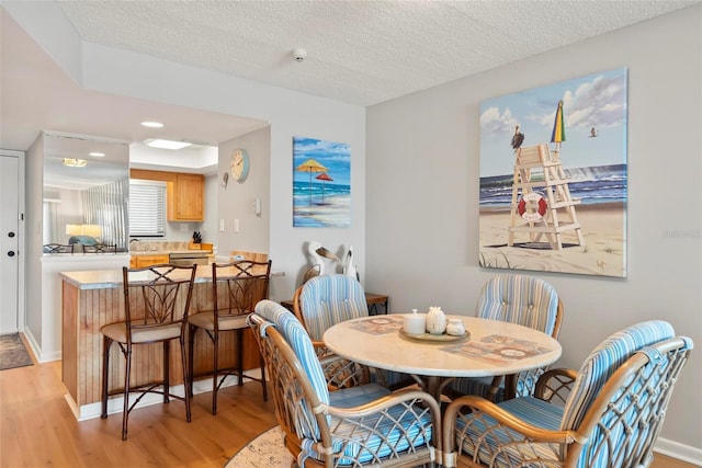 dining space with light hardwood / wood-style flooring and a textured ceiling