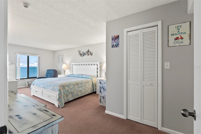 carpeted bedroom featuring a textured ceiling, a water view, and a closet