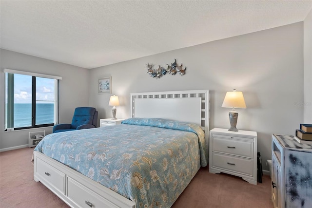 bedroom with carpet floors, a water view, and a textured ceiling