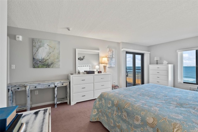 bedroom featuring access to exterior, a textured ceiling, a water view, and dark carpet