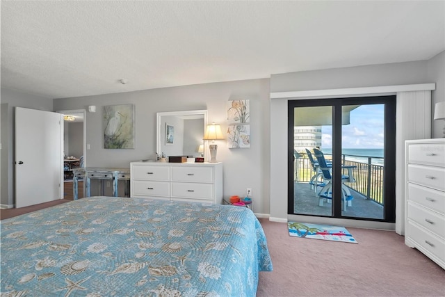 carpeted bedroom featuring a textured ceiling, access to outside, and a water view