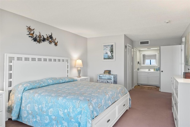 bedroom with ensuite bathroom, sink, carpet flooring, a textured ceiling, and a closet