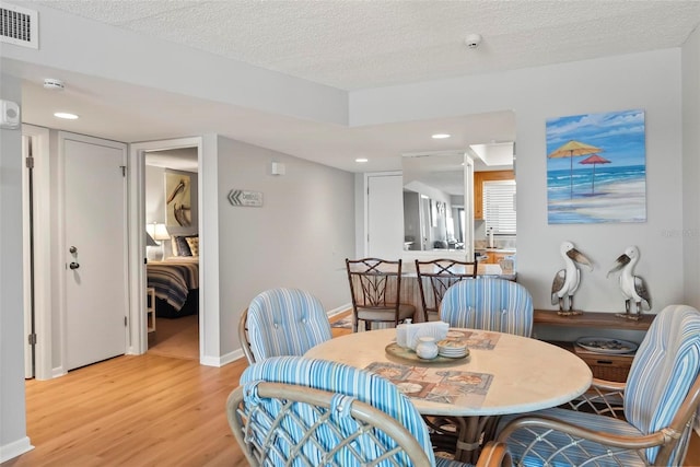 dining area featuring a textured ceiling and light hardwood / wood-style floors