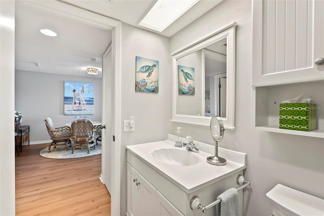 bathroom with toilet, vanity, and hardwood / wood-style flooring