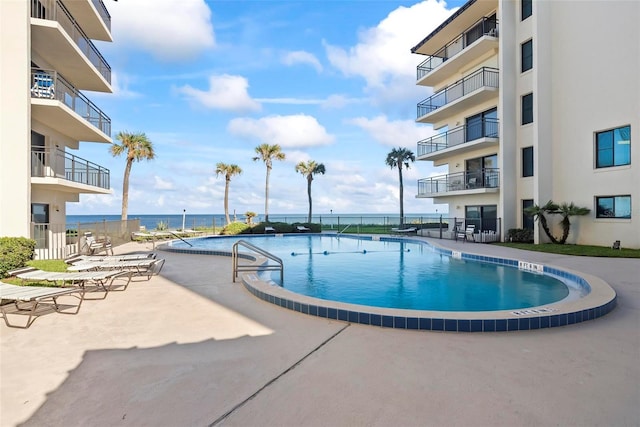 view of swimming pool with a patio area and a water view