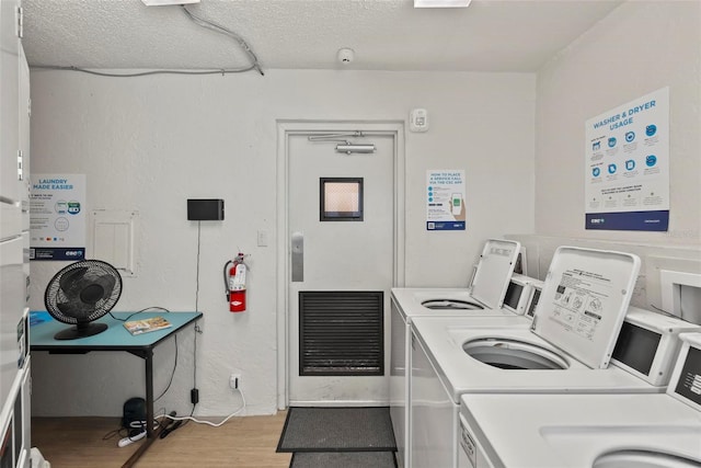 clothes washing area featuring washing machine and dryer, light hardwood / wood-style flooring, stacked washing maching and dryer, and a textured ceiling