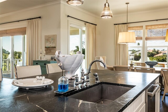 kitchen with pendant lighting, plenty of natural light, ornamental molding, and sink