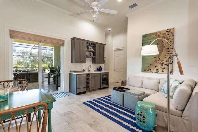 living room with wine cooler, ceiling fan, sink, and ornamental molding