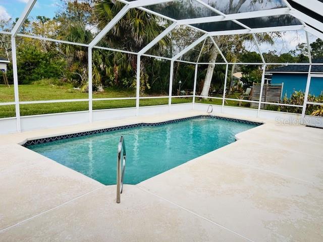 view of swimming pool with glass enclosure and a patio