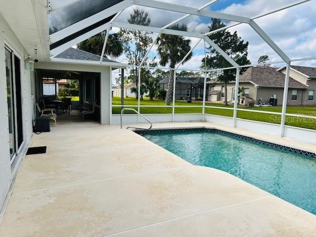 view of pool featuring glass enclosure and a patio area