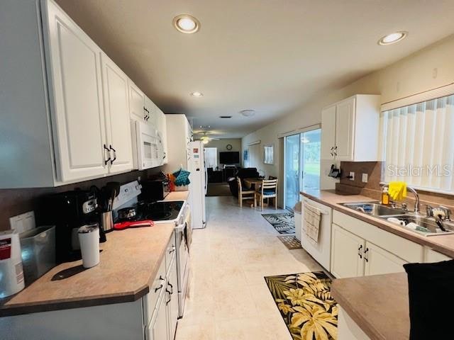 kitchen featuring sink, light tile patterned flooring, white appliances, decorative backsplash, and white cabinets