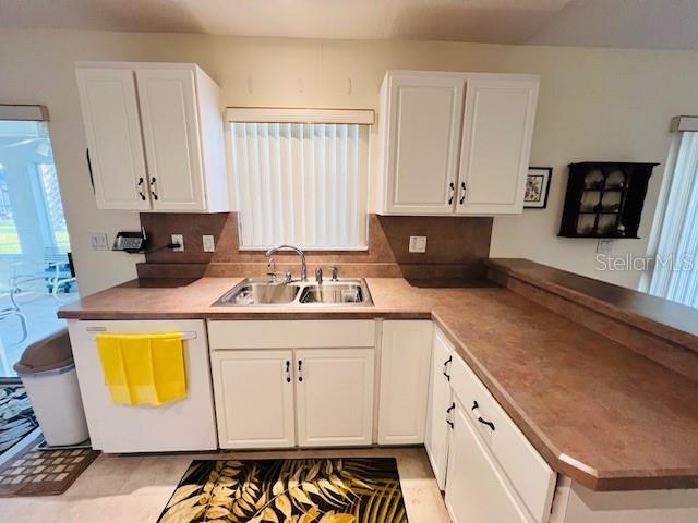 kitchen with dishwasher, white cabinetry, and sink