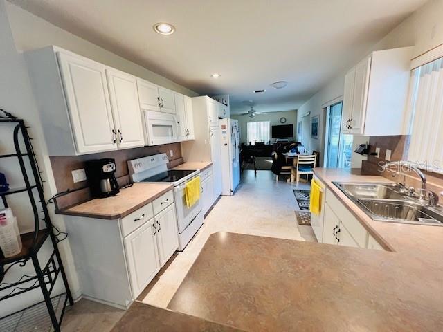 kitchen featuring white cabinetry, sink, ceiling fan, and white appliances