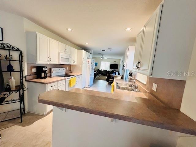 kitchen featuring white cabinetry, white appliances, kitchen peninsula, and sink