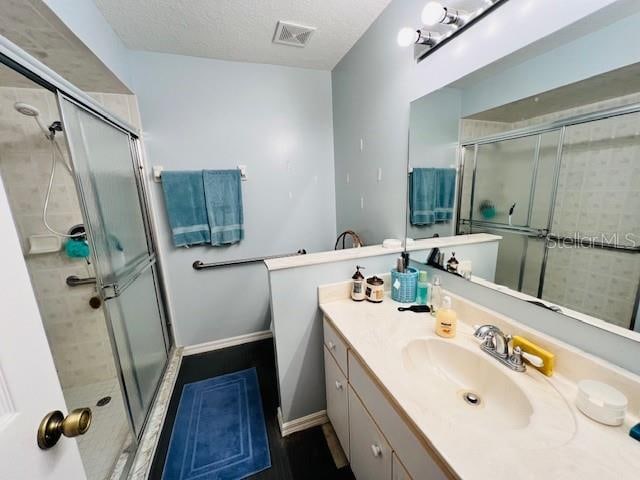 bathroom featuring a textured ceiling, vanity, and a shower with door