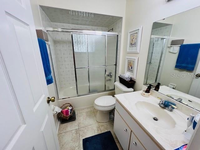 full bathroom with combined bath / shower with glass door, vanity, toilet, and tile patterned flooring