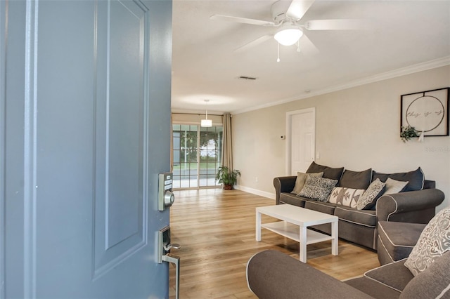 living room with light hardwood / wood-style floors, ceiling fan, and ornamental molding