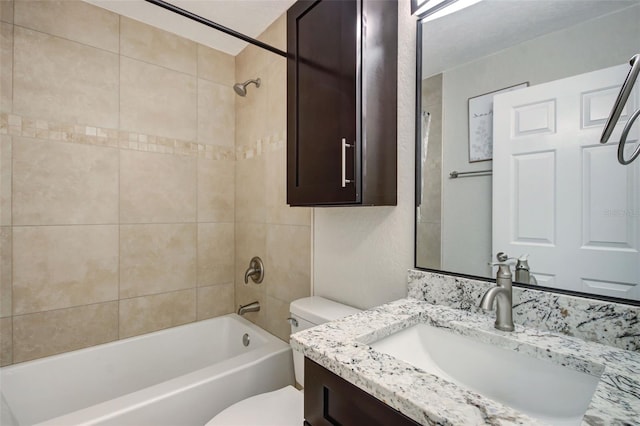 full bathroom featuring vanity, tiled shower / bath combo, and toilet