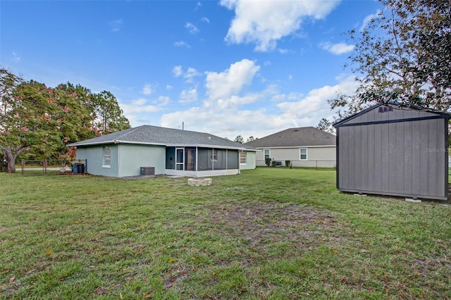 rear view of house featuring central AC, a lawn, and a storage unit