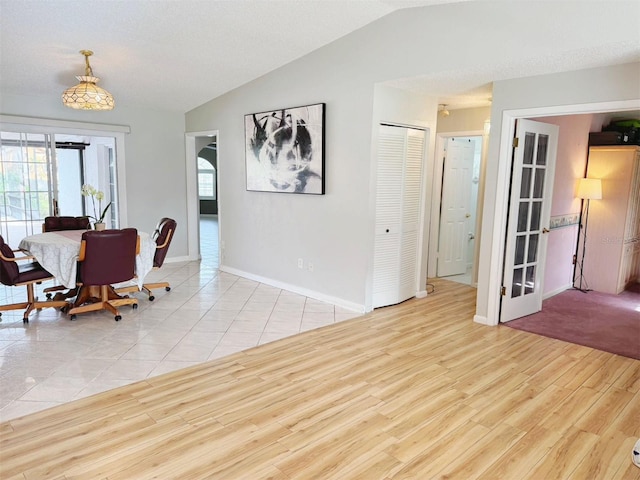 dining space with vaulted ceiling, french doors, a textured ceiling, and light hardwood / wood-style flooring