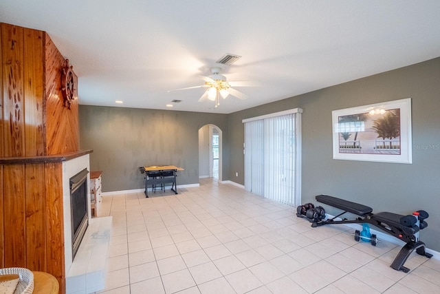 interior space featuring a fireplace, ceiling fan, and light tile patterned flooring