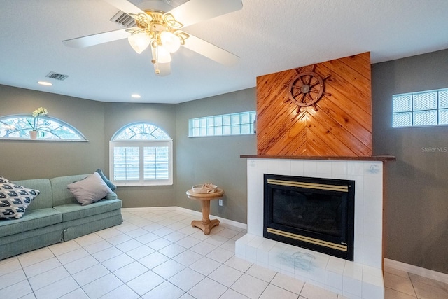 living room featuring ceiling fan, light tile patterned floors, and a tiled fireplace