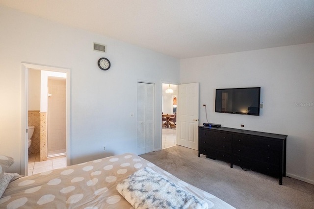 carpeted bedroom featuring ensuite bath and a closet