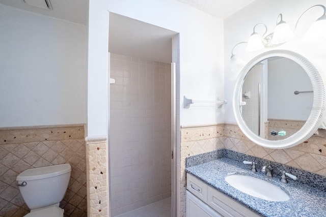 bathroom featuring tiled shower, vanity, toilet, and tile walls