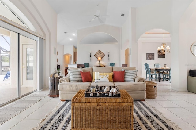 tiled living room with ceiling fan with notable chandelier and high vaulted ceiling