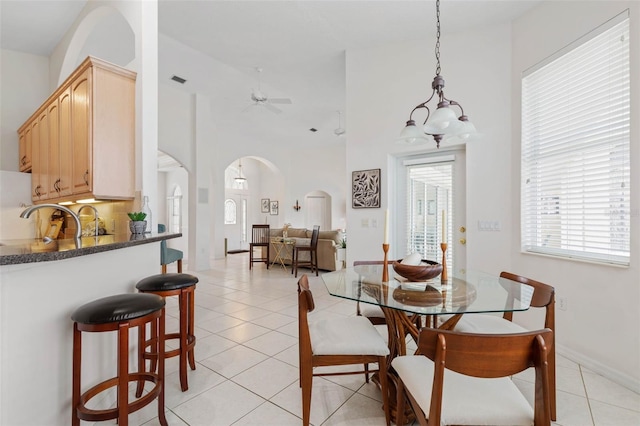 dining area featuring ceiling fan, a towering ceiling, and light tile patterned floors