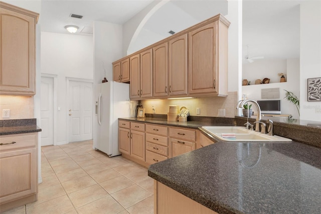 kitchen with sink, light tile patterned flooring, white fridge with ice dispenser, and light brown cabinets