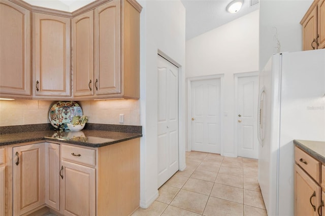 34 Clermont Ct, Palm Coast, FL 32137 - kitchen with freestanding refrigerator, light brown cabinetry, backsplash, dark countertops, and light tile patterned flooring