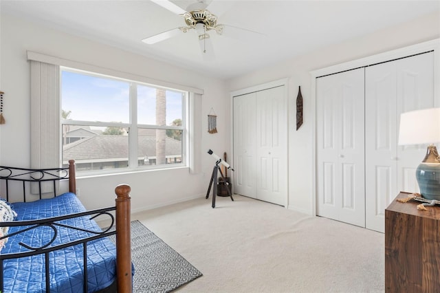 carpeted bedroom featuring ceiling fan and two closets