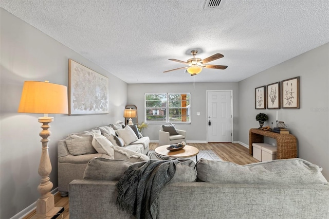 living room with ceiling fan, a textured ceiling, and light hardwood / wood-style floors