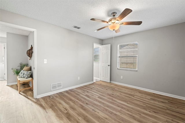 spare room with a textured ceiling, wood-type flooring, and ceiling fan