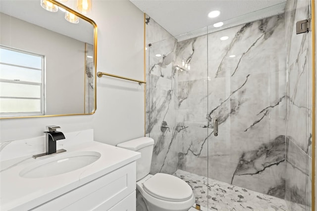 bathroom with a shower with door, vanity, and toilet