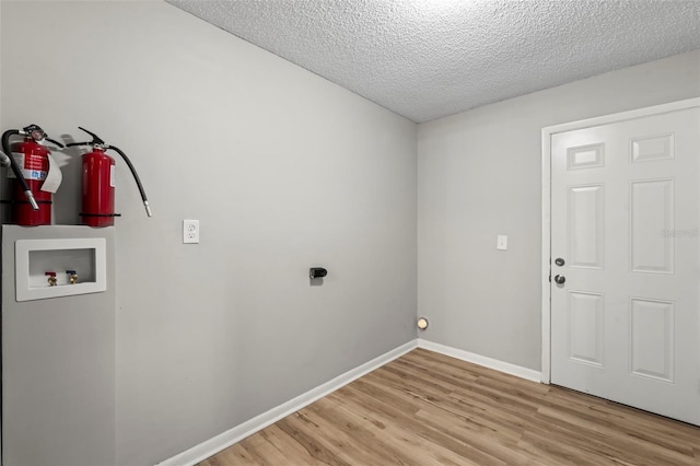 laundry area featuring light wood-type flooring, washer hookup, and a textured ceiling