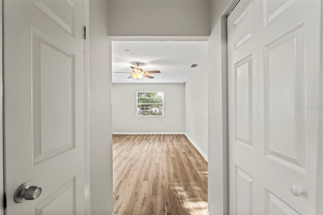 corridor with light hardwood / wood-style floors and a textured ceiling