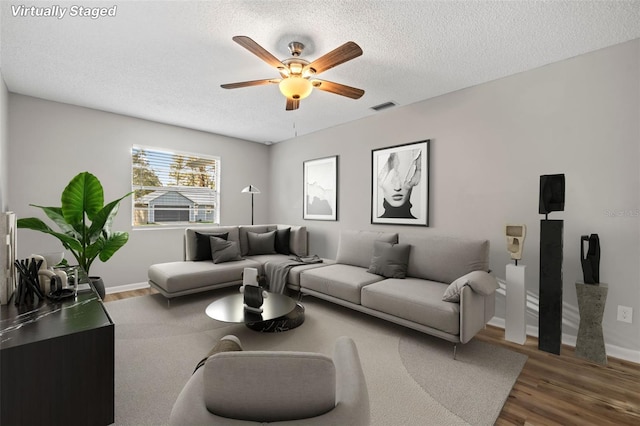 living room featuring hardwood / wood-style floors, ceiling fan, and a textured ceiling