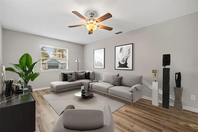 living room featuring light wood-type flooring, a textured ceiling, and ceiling fan