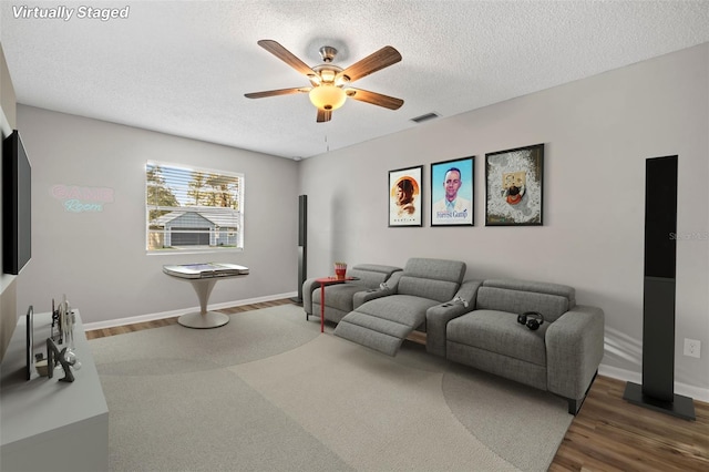 living room with ceiling fan, dark hardwood / wood-style floors, and a textured ceiling