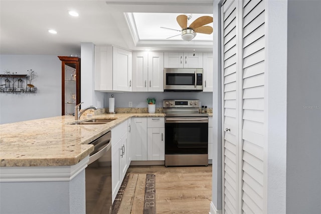 kitchen featuring white cabinetry, light stone counters, light hardwood / wood-style flooring, kitchen peninsula, and appliances with stainless steel finishes